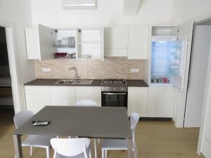 a kitchen with white cabinets and a table and chairs at Morfeo appartamenti e camere in Palmi