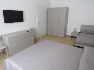 a white bedroom with a bed and a tv at Morfeo appartamenti e camere in Palmi