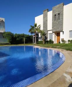 a large blue swimming pool in front of a building at Villa blancha beach sidi rahal in Sidi Rahal