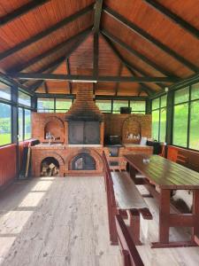 a large room with a brick fireplace and a wooden table at Pensiunea agroturistica Elena in Drăgoiasa