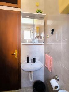 Un baño con un lavabo blanco y un espejo. en REA APARTMENT, en Kragujevac