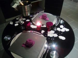 une table noire avec une bougie et des roses violettes dessus dans l'établissement Charmant studio à Baixas de 30 m² avec Jacuzzi, à Baixas