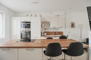 a kitchen with white cabinets and a wooden counter top at Maison des Clos Biais in Dinard