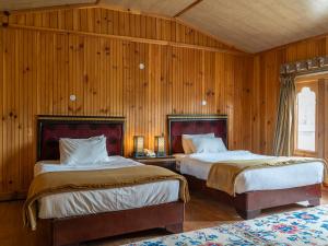 2 Betten in einem Zimmer mit holzgetäfelten Wänden in der Unterkunft Tiger's Nest Resort - Best Resort In Paro in Paro