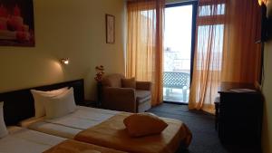 una stanza d'albergo con un letto, una sedia e una finestra di Hotel Blian a Ravda