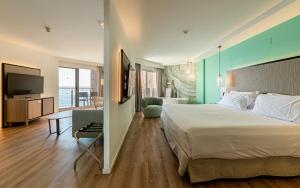 a bedroom with a large bed and a living room at INNSiDE by Meliá Alicante Porta Maris in Alicante