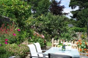 a table and chairs in a garden with flowers at Peak District Luxury cottage, sleeps 8 plus pets in Tideswell