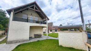 a large white house with a balcony on a yard at Gîtes Ange et Bacchus in Villecresnes