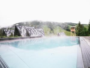a large swimming pool with a mountain in the background at TRIFORET alpin resort by Falkensteiner in Hinterstoder +38 photos