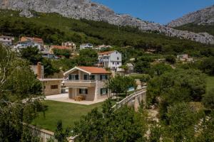 a house in a village with mountains in the background at Zvonimir Holiday with large 95m2 pool in Solin