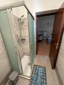 una ducha con puerta de cristal en un baño en Nostra casa rooms, en Palermo