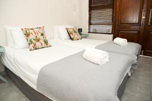 two beds in a room with white sheets and towels at Die Aalwyntjie in Riversdale