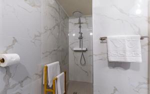 a bathroom with a shower with white marble walls at Hotel Koral in Medulin +66 photos