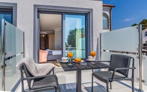 a balcony with a table with two glasses of orange juice at Hotel Koral in Medulin