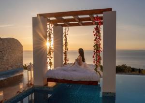a woman is sitting on a bed in a pool at Emerald Villas & Suites - The Finest Hotels Of The World in Agios Nikolaos