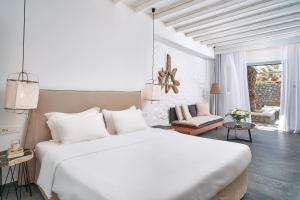 a white bedroom with a large bed and a living room at Hippie Chic Hotel in Agios Ioannis Mykonos
