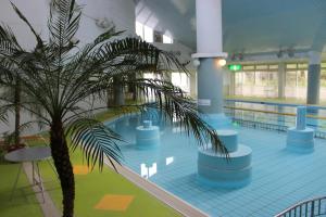 une piscine intérieure avec un palmier dans un bâtiment dans l'établissement Ikoinomura Iwate, à Hachimantai
