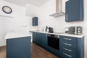 a kitchen with blue cabinets and a clock on the wall at Host & Stay - Sanderling Chase in Scarborough