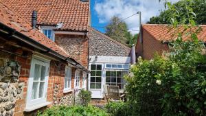 een stenen huis met een stoel ervoor bij Honey Barrel Cottage in Stiffkey