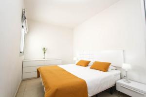 a white bedroom with a large bed with orange sheets at Fabuloso ático en el centro in Arguineguín