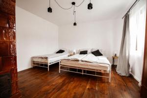 two beds in a white room with wooden floors at Sielanka Roztocze in Pary