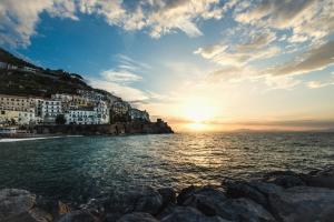 a sunset over the ocean with buildings on a hill at Amalfi Luxury House in Amalfi