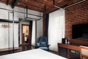 a bedroom with a bed and a chair and a television at DeCamondo Galata, a Tribute Portfolio Hotel in Istanbul