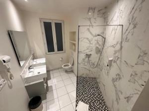 a bathroom with a shower and a sink and a toilet at Hotel Richmond Gare du Nord in Paris