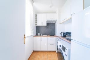 a kitchen with white cabinets and a sink at Résidence Gabrielle - Proche de Paris in Bondy +6 photos