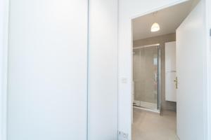 a hallway with white walls and a glass door at Résidence Gabrielle - Proche de Paris in Bondy