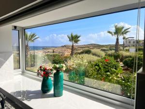 two vases sitting on a window sill with a view of the ocean at True front line apartment in Tatlisu North Cyprus in Küçükerenköy