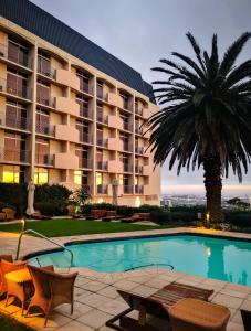 een hotel met een palmboom en een zwembad bij Garden Court Nelson Mandela Boulevard in Kaapstad