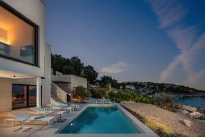 a house with a swimming pool and lounge chairs at Luxusvilla Marim in Stara Baška