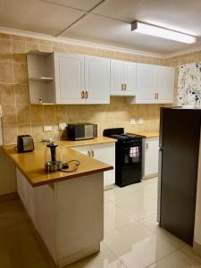 a kitchen with white cabinets and a black refrigerator at SinoT Short Stays in Pietermaritzburg +13 photos