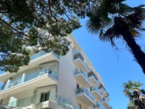 an apartment building with white balconies and a palm tree at Hotel President in Lido di Jesolo