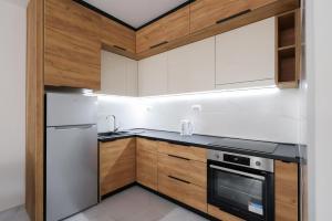 una cucina con elettrodomestici bianchi e armadietti in legno di Apartman Biser 5 a Ruma Altre 4 foto