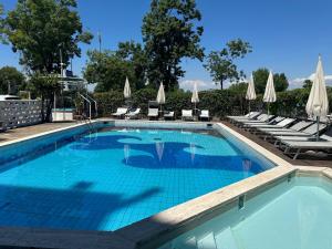 a large swimming pool with lounge chairs and umbrellas at Hotel President in Lido di Jesolo