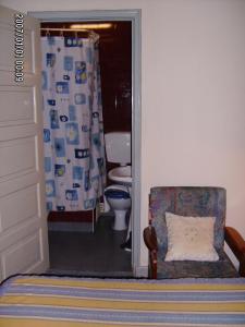 a bathroom with a toilet and a chair at Olhos Pretos in Caldas da Rainha