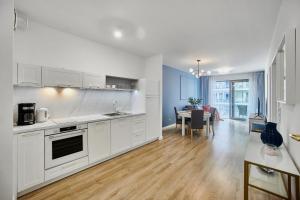 a kitchen with white cabinets and a dining room at Balticus Apartament Promenada Gwiazd 14 in Międzyzdroje +3 photos