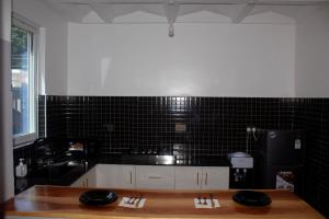a kitchen with a wooden table and a black tile wall at AC one bedroom apartment , 5 min walk from bofa road, baobab resort ,Canna Lily in Kilifi +30 photos