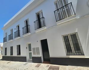 a white building with black doors and windows at apartamentos terraza Chiclana centro ciudad in Chiclana de la Frontera