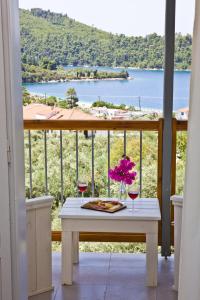 a table on a balcony with a view of the water at Skalopati Studios & Villa in Panormos Skopelos