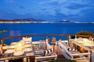 a table on a deck with a view of the water at R&G luxury accommodation Varkiza in Vari