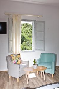 a living room with two chairs and a table and a window at Skalopati Studios & Villa in Panormos Skopelos