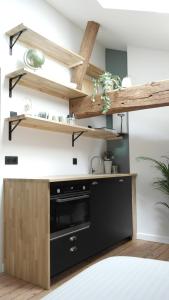 a kitchen with wooden shelves on the wall at La Curiosité, Et Pop Et Chic ! in Poitiers
