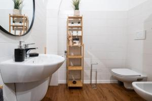 Un baño con lavabo, inodoro y espejo. en House Visconti, en Bari