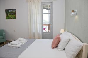 a bedroom with a white bed with pillows and a window at Skalopati Studios & Villa in Panormos Skopelos
