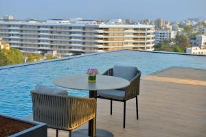 a table and chairs on a balcony with a pool at Treat Hotel Nashik City Center in Nashik