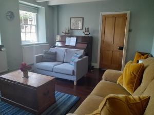 a living room with a couch and a piano at The Captain's House Charlestown St Austell in Charlestown +36 photos