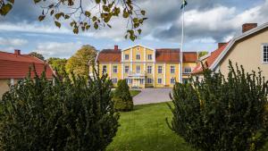 a large yellow house with trees in the yard at Ronnums Herrgård in Vargön